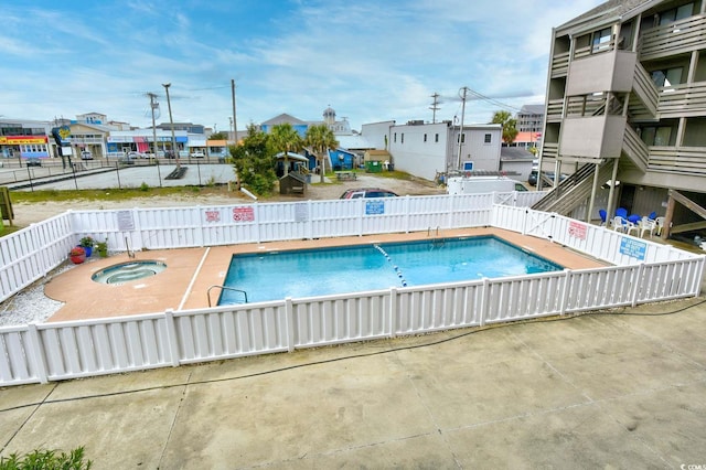 community pool with a patio area, a hot tub, and a fenced backyard