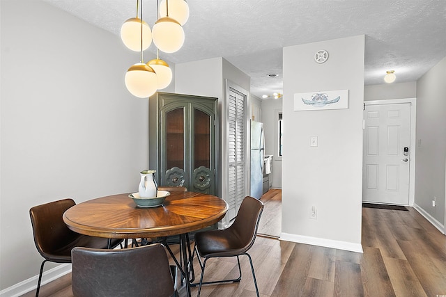 dining room with a textured ceiling and dark hardwood / wood-style flooring