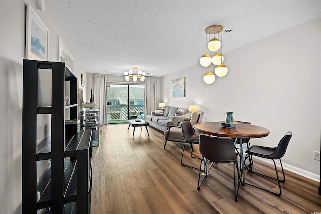 dining space featuring hardwood / wood-style floors, a textured ceiling, and a chandelier