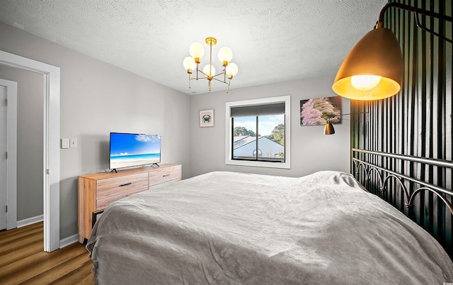 bedroom with a notable chandelier, a textured ceiling, and dark wood-type flooring