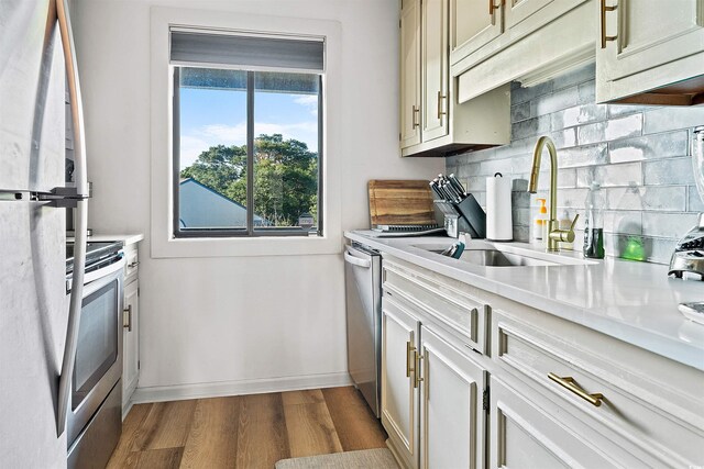 kitchen with decorative backsplash, hardwood / wood-style flooring, sink, cream cabinetry, and stainless steel appliances