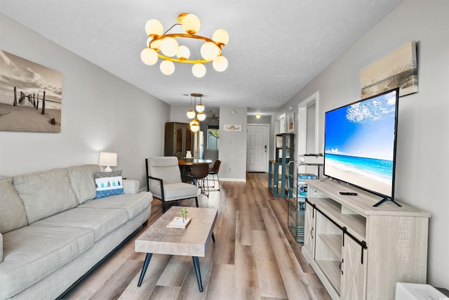 living room with a notable chandelier, a textured ceiling, and light wood-type flooring