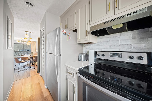 kitchen featuring extractor fan, electric range, an inviting chandelier, light wood-type flooring, and a textured ceiling