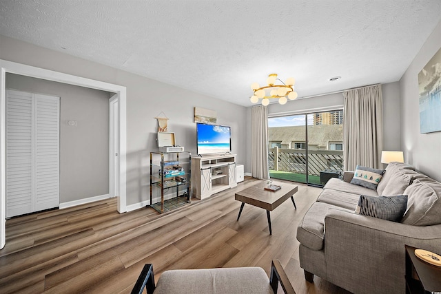 living room with an inviting chandelier, a textured ceiling, and wood-type flooring