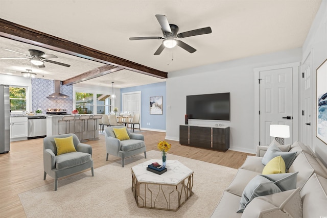 living room featuring beam ceiling, light hardwood / wood-style flooring, and ceiling fan