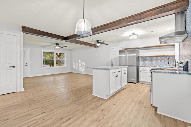 kitchen featuring white cabinets, decorative light fixtures, wall chimney exhaust hood, stainless steel refrigerator, and light wood-type flooring