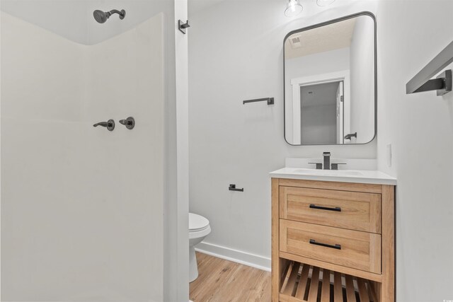 bathroom with vanity, walk in shower, toilet, and wood-type flooring