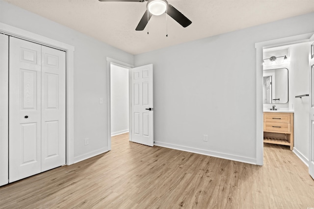 unfurnished bedroom with ensuite bathroom, light wood-type flooring, ceiling fan, a closet, and sink