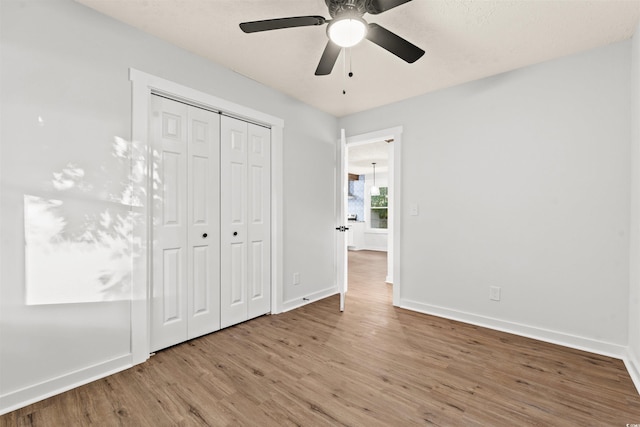 unfurnished bedroom with wood-type flooring, a closet, and ceiling fan