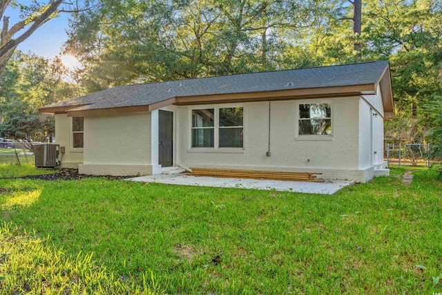 back of property with central AC and a lawn