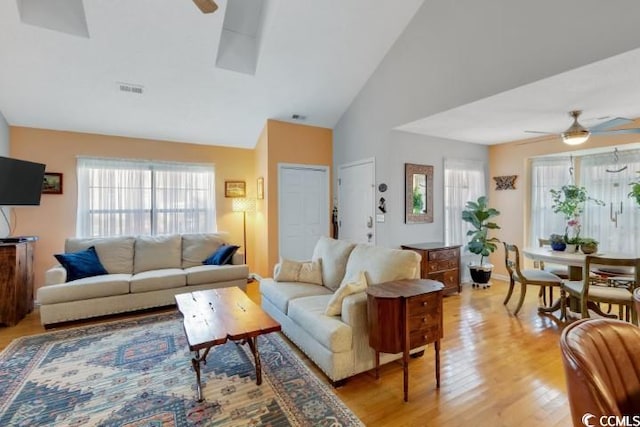 living room featuring light hardwood / wood-style floors, a healthy amount of sunlight, high vaulted ceiling, and ceiling fan