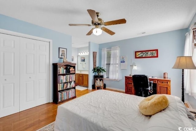 bedroom featuring ensuite bathroom, light wood-type flooring, a closet, and ceiling fan