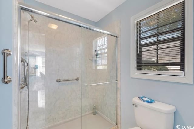 bathroom featuring a shower with door and toilet