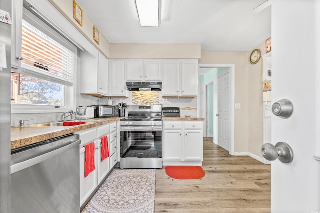 kitchen featuring light hardwood / wood-style flooring, sink, backsplash, appliances with stainless steel finishes, and white cabinets