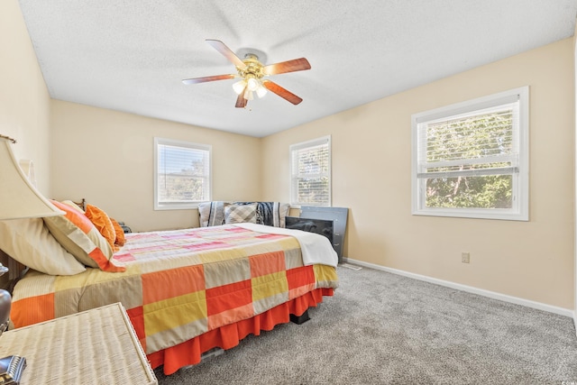 carpeted bedroom featuring ceiling fan and a textured ceiling