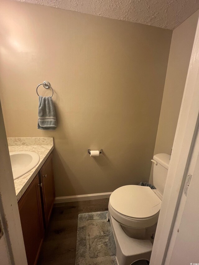 bathroom with toilet, hardwood / wood-style flooring, a textured ceiling, and vanity