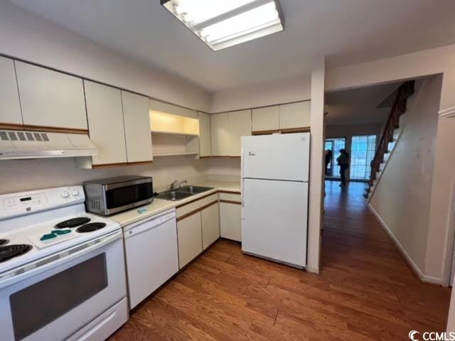 kitchen featuring hardwood / wood-style floors, white cabinetry, white appliances, and sink