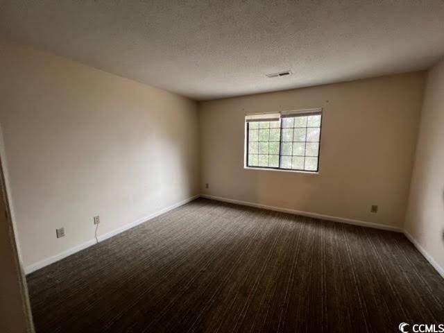 unfurnished room featuring dark hardwood / wood-style flooring and a textured ceiling