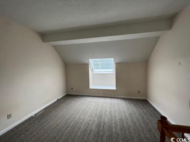 additional living space with lofted ceiling and dark colored carpet