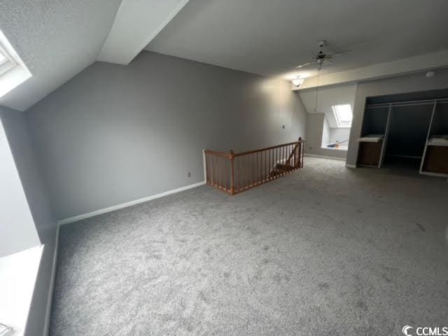 bonus room with carpet flooring, ceiling fan, and vaulted ceiling with skylight