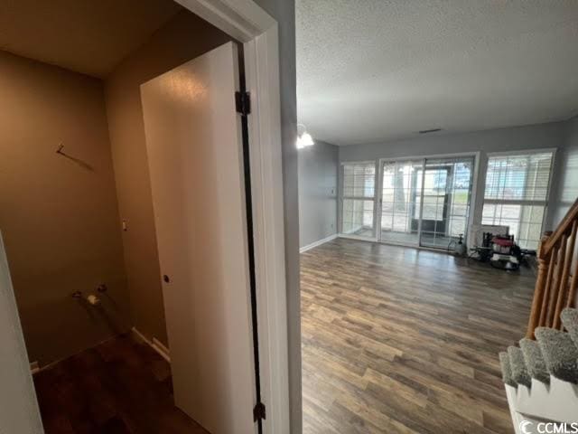 corridor with dark hardwood / wood-style floors and a textured ceiling