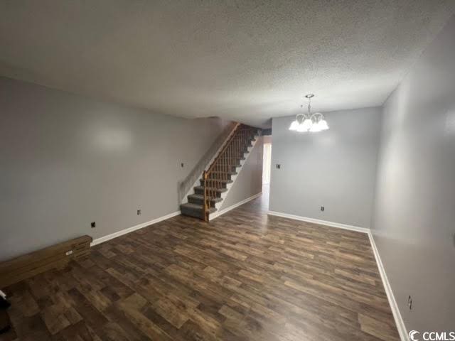 spare room with dark hardwood / wood-style flooring, a textured ceiling, and an inviting chandelier