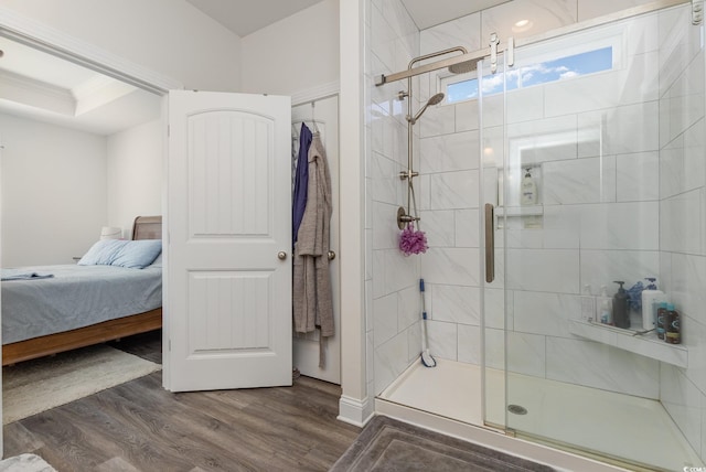 bathroom with a shower with door, crown molding, and wood-type flooring