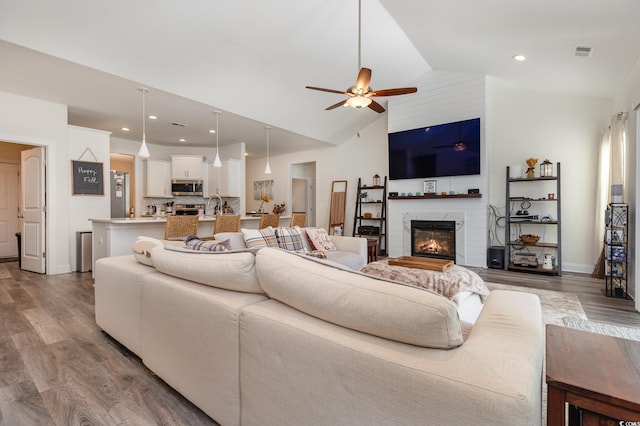 living room featuring ceiling fan, high vaulted ceiling, sink, and hardwood / wood-style floors