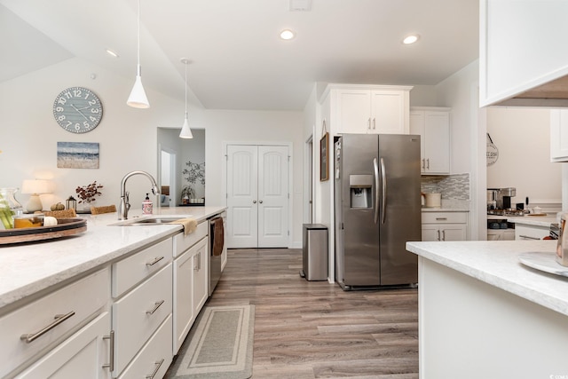 kitchen featuring white cabinets, backsplash, light hardwood / wood-style flooring, pendant lighting, and stainless steel appliances