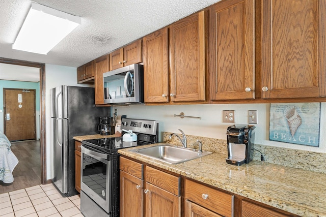 200 76th Ave N Unit 1106, Myrtle Beach, SC 29572 - kitchen featuring stainless steel appliances, a sink, brown cabinets, a textured ceiling, and light tile patterned flooring