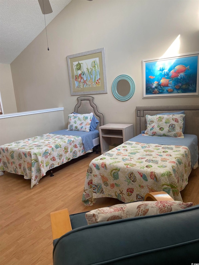 bedroom with ceiling fan, hardwood / wood-style flooring, a textured ceiling, and vaulted ceiling