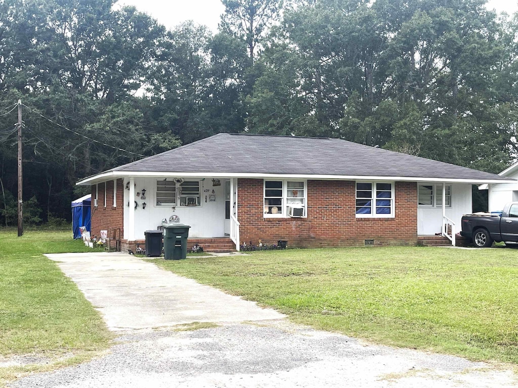 ranch-style home featuring cooling unit and a front lawn