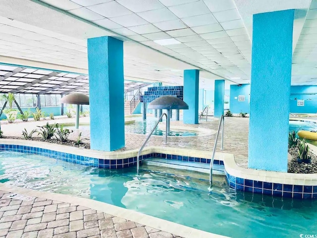 view of swimming pool featuring a patio and an indoor in ground hot tub