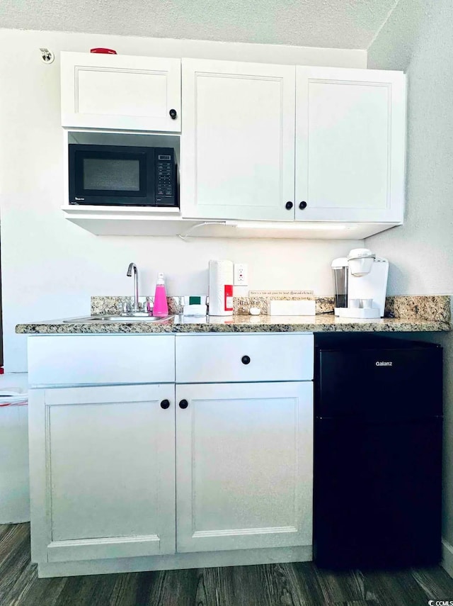 kitchen featuring dark wood-type flooring, black appliances, white cabinetry, light stone counters, and a textured ceiling