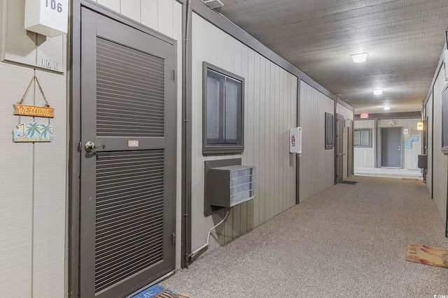 hallway with carpet floors and wood walls