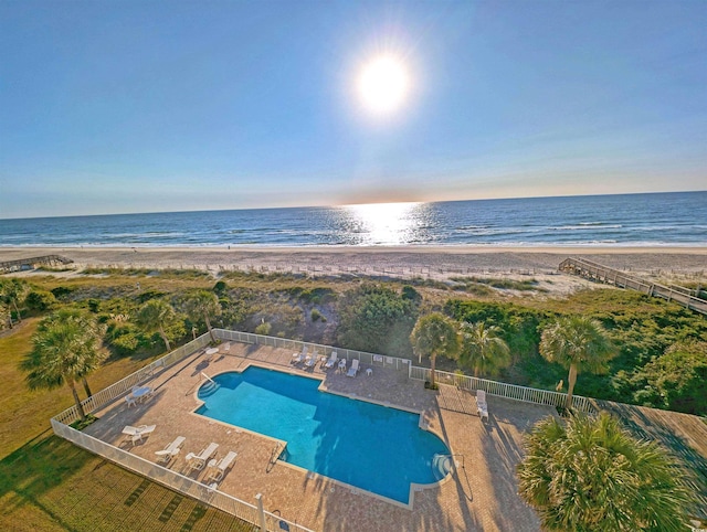 view of pool featuring a water view, a patio area, and a beach view