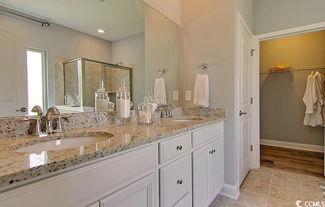 full bathroom featuring a sink, double vanity, a spacious closet, and a stall shower
