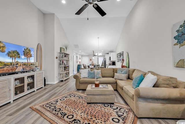 living room with light hardwood / wood-style flooring, high vaulted ceiling, and ceiling fan with notable chandelier