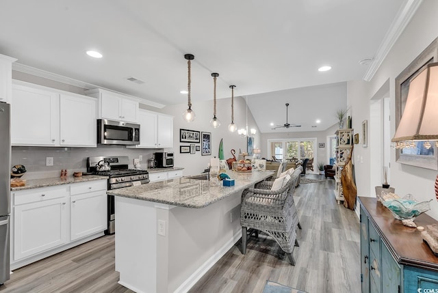 kitchen featuring appliances with stainless steel finishes, white cabinets, a kitchen island with sink, and hanging light fixtures