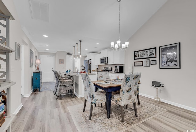 dining space with a notable chandelier, high vaulted ceiling, and light wood-type flooring