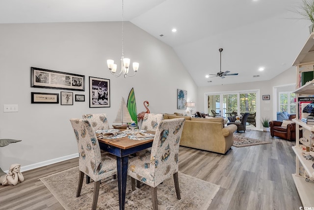 dining area featuring high vaulted ceiling, wood-type flooring, and ceiling fan with notable chandelier