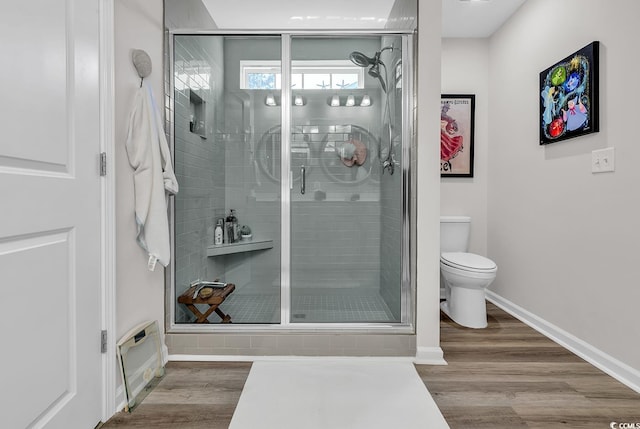 bathroom featuring hardwood / wood-style floors, a shower with shower door, and toilet