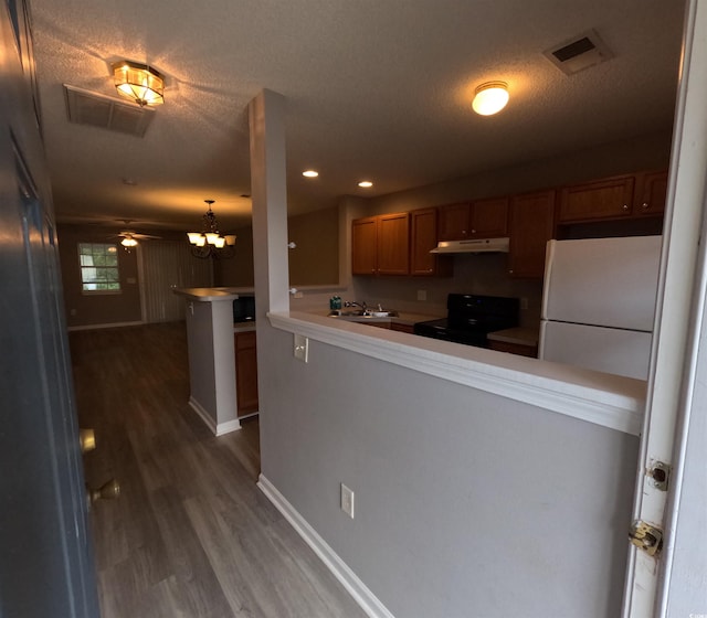 kitchen featuring kitchen peninsula, a textured ceiling, black range with electric stovetop, dark hardwood / wood-style floors, and pendant lighting