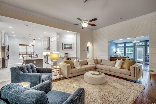 living room with ceiling fan, ornamental molding, light hardwood / wood-style flooring, and sink