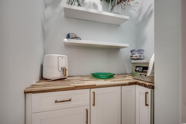 bar featuring butcher block counters and white cabinetry