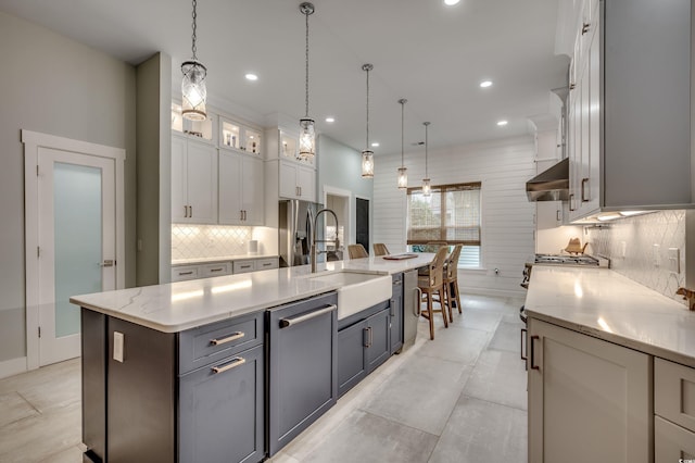 kitchen featuring a large island, decorative light fixtures, sink, white cabinets, and appliances with stainless steel finishes