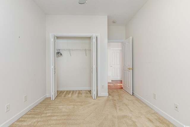 unfurnished bedroom with a closet and light colored carpet