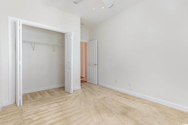 unfurnished bedroom with ceiling fan, a closet, and light carpet