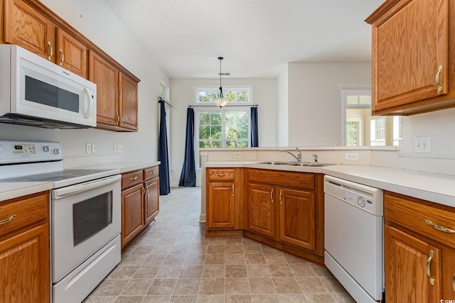 kitchen featuring white appliances, decorative light fixtures, and sink