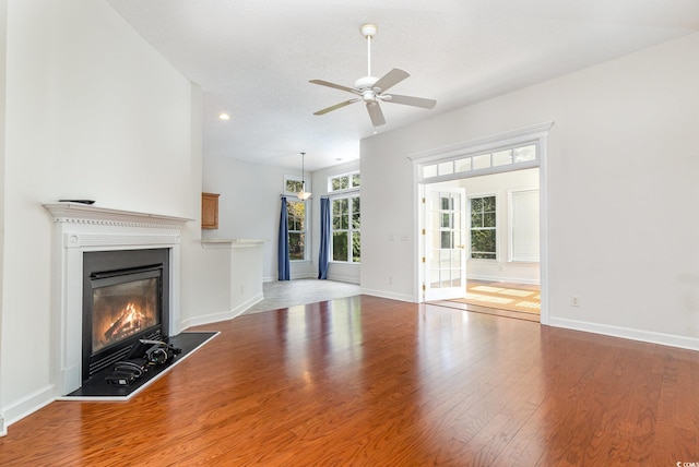 unfurnished living room with ceiling fan, wood-type flooring, and a textured ceiling